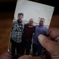 Daniel Guess holds a photograph of himself, right, along with his father, Larry Guess, center, and brother David Guess, left, on Thursday, June 23, 2022, in Athens, Ala. David Guess, 51, was killed by gun violence in March. Guess’ death began with an argument over a car part. (AP Photo/Brynn Anderson)