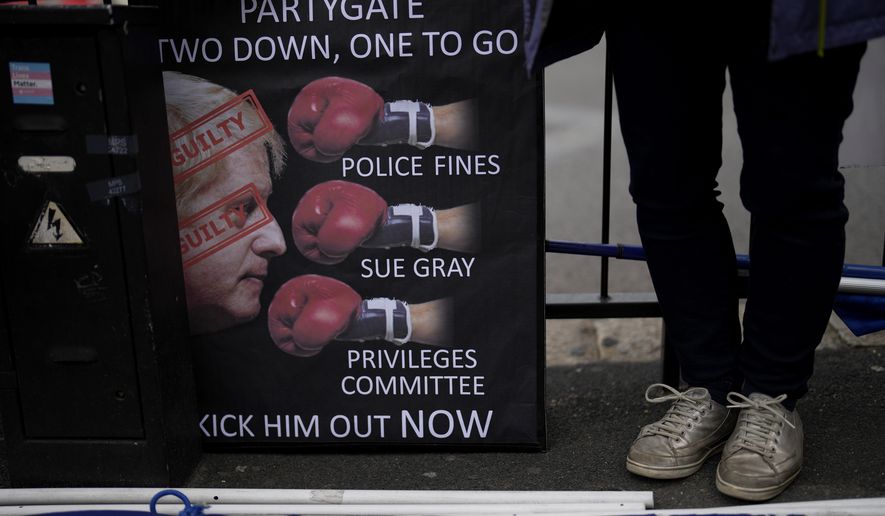 An anti-Boris Johnson, anti-Brexit protester stands next to a placard across the street from the Houses of Parliament on the edge of Parliament Square, in London, Wednesday, May 25, 2022. Johnson was dealt a major blow Tuesday, July 5, 2022 when two of his most senior Cabinet ministers quit, saying they had lost confidence in Johnson’s leadership.  (AP Photo/Matt Dunham, File)