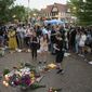 Dozens of mourners gather for a vigil near Central Avenue and St. Johns Avenue in downtown Highland Park, one day after a gunman killed at least seven people and wounded dozens more by firing an AR-15-style rifle from a rooftop onto a crowd attending Highland Park&#39;s Fourth of July parade, Tuesday, July 5, 2022 in Highland Park, Ill.. (Anthony Vazquez/Chicago Sun-Times via AP)