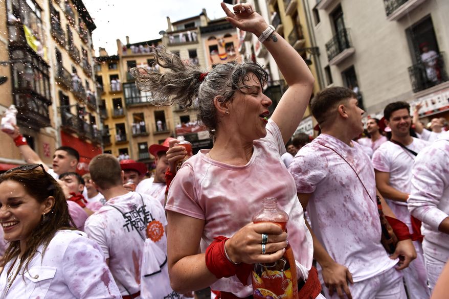Revelers celebrate while waiting for the launch of the &#39;Chupinazo&#39; rocket, to mark the official opening of the 2022 San Fermin fiestas in Pamplona, Spain, Wednesday, July 6, 2022. The blast of a traditional firework opens Wednesday nine days of uninterrupted partying in Pamplona&#39;s famed running-of-the-bulls festival which was suspended for the past two years because of the coronavirus pandemic. (AP Photo/Alvaro Barrientos)