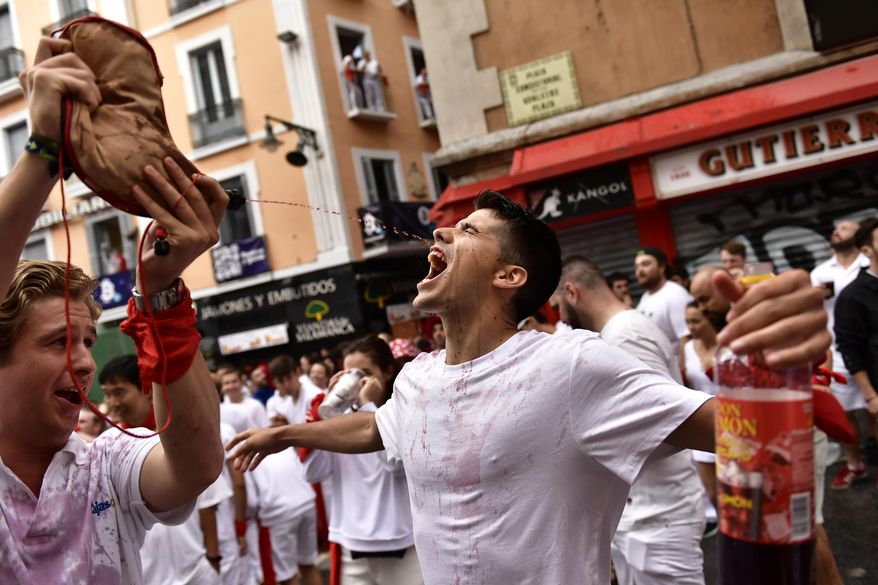 A reveler drinks from a wineskin while waiting for the launch of the &#x27;Chupinazo&#x27; rocket, to mark the official opening of the 2022 San Fermin fiestas in Pamplona, Spain, Wednesday, July 6, 2022. The blast of a traditional firework opens Wednesday nine days of uninterrupted partying in Pamplona&#x27;s famed running-of-the-bulls festival which was suspended for the past two years because of the coronavirus pandemic. (AP Photo/Alvaro Barrientos)