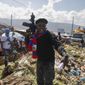 Barbecue, the leader of the &amp;quot;G9 and Family&amp;quot; gang, stands next to garbage to call attention to the conditions people live in as he leads a march against kidnapping through La Saline neighborhood in Port-au-Prince, Haiti, Friday, Oct. 22, 2021. The group said they were also protesting poverty and for justice in the slaying of President Jovenel Moise. (AP Photo/Odelyn Joseph, File)