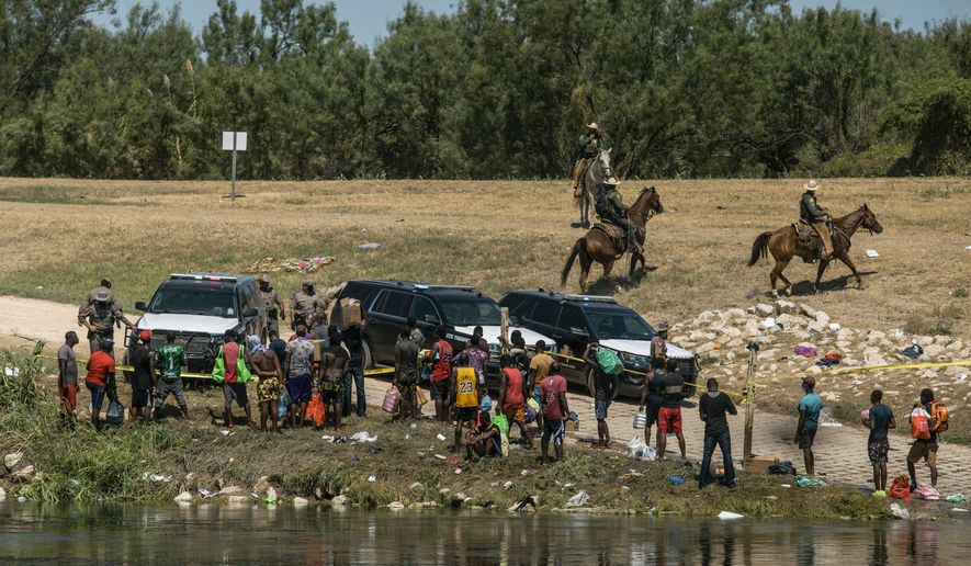 FILE - U.S. border patrol officers contain a group of migrants on the shore of the Rio Grande after they crossed from Ciudad Acuña, Mexico, into Del Rio, Texas, Sept. 19, 2021. Border Patrol agents on horseback engaged in &quot;unnecessary use of force&quot; against non-threatening Haitian immigrants but didn&#x27;t whip any with their reins, according to a federal investigation of chaotic scenes along the Texas-Mexico border last fall. (AP Photo/Felix Marquez, File)