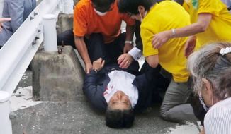 In this image from a video, Japan’s former Prime Minister Shinzo Abe, center, is attended on the ground in Nara, western Japan Friday, July 8, 2022. Abe was shot and critically wounded during a campaign speech Friday. He was airlifted to a hospital but officials said he was not breathing and his heart had stopped. (Kyodo News via AP)