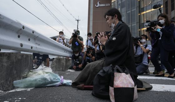 A man prays in front of a makeshift memorial at the scene where the former Prime Minister Shinzo Abe was shot while delivering his speech to support the Liberal Democratic Party&#39;s candidate during an election campaign in Nara, western Japan, Friday, July 8, 2022. Former Prime Minister Shinzo Abe was assassinated Friday on a street in western Japan by a gunman who opened fire on him from behind as he delivered a campaign speech — an attack that stunned the nation that has some of the strictest gun control laws anywhere. (AP Photo/Hiro Komae)