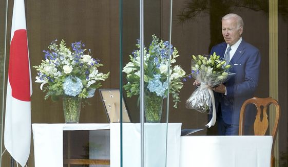 President Joe Biden holds a bouquet as he arrives to sign a condolence book at the Japanese ambassador&#39;s residence in Washington, Friday, July 8, 2022, for former Japanese Prime Minister Shinzo Abe who was assassinated on Friday while campaigning. (AP Photo/Susan Walsh)