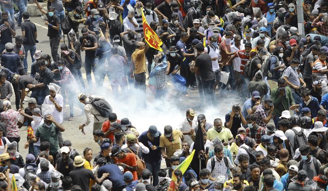 Protesters react as a tear gas shell fired by police lands next to them in Colombo, Sri Lanka, Saturday, July 9, 2022. Sri Lankan protesters demanding that President Gotabaya Rajapaksa resign forced their way into his official residence on Saturday, a local television report said, as thousands of people took to the streets in the capital decrying the island nation&#x27;s worst economic crisis in recent memory. (AP Photo/Amitha Thennakoon)
