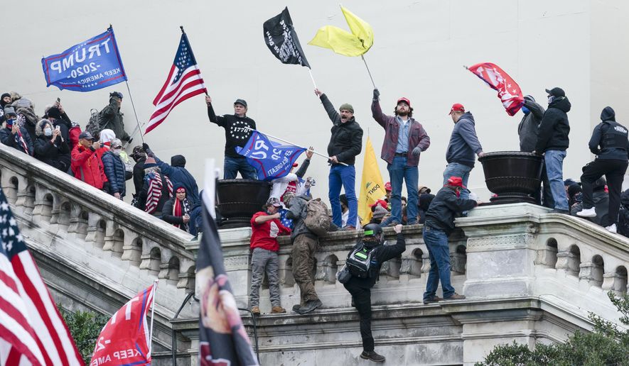 Rioters wave flags on the West Front of the U.S. Capitol in Washington on Jan. 6, 2021. As public trust in democratic institutions declines, conspiracy theories are filling the void. In some cases, that's leading believers to doubt even their own allies. (AP Photo/Jose Luis Magana, File)