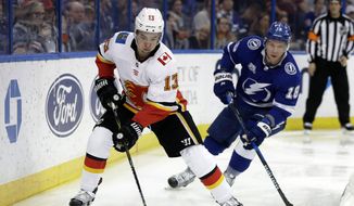 Calgary Flames left wing Johnny Gaudreau (13) carries the puck past Tampa Bay Lightning left wing Ondrej Palat (18) during the third period of an NHL hockey game, Jan. 11, 2018, in Tampa, Fla. Executives around the NHL expect plenty of movement before free agency opens Wednesday, July 13, 2022. Several top players including Gaudreau and Palat could still sign contracts prior to hitting the open market. (AP Photo/Chris O&#39;Meara, file) **FILE**