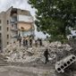 Rescue workers stand on the rubble at the scene in the after math of a missile strike that his a residential apartment block, in Chasiv Yar, Donetsk region, eastern Ukraine, Sunday, July 10, 2022. (AP Photo/Nariman El-Mofty)