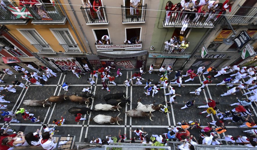 People run in the street with fighting bulls and steers during the running of the bulls at the San Fermin Festival in Pamplona, northern Spain, Sunday, July 10, 2022. Revellers from around the world flock to Pamplona every year for nine days of uninterrupted partying in Pamplona&#39;s famed running of the bulls festival which was suspended for the past two years because of the coronavirus pandemic. (AP Photo/Alvaro Barrientos)