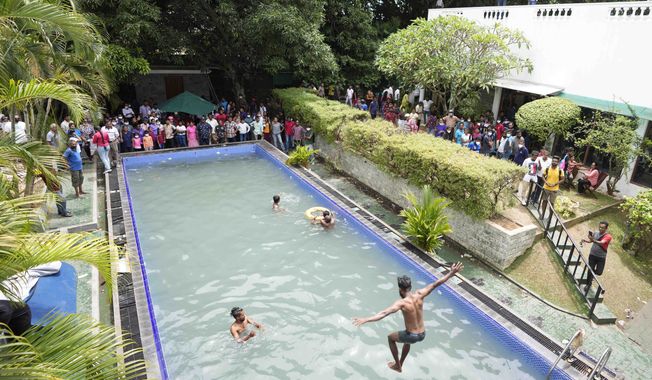 Protesters swim as onlookers wait at a swimming pool in the president&#x27;s official residence a day after it was stormed in Colombo, Sri Lanka, Sunday, July 10, 2022. Sri Lanka’s opposition political parties will meet Sunday to agree on a new government a day after the country’s president and prime minister offered to resign in the country’s most chaotic day in months of political turmoil, with protesters storming both officials’ homes and setting fire to one of the buildings in a rage over the nation’s economic crisis. (AP Photo/Eranga Jayawardena)