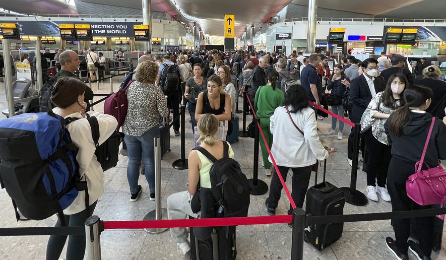 FILE - Travellers queue at security at Heathrow Airport in London, Wednesday, June 22, 2022. London’s Heathrow Airport  apologized Monday, July 11, 2022 to passengers whose travels have been disrupted by staff shortages. The airport warned that it may ask airlines to cut more flights from their summer schedules to reduce the strain if the chaos persists. (AP Photo/Frank Augstein, File)