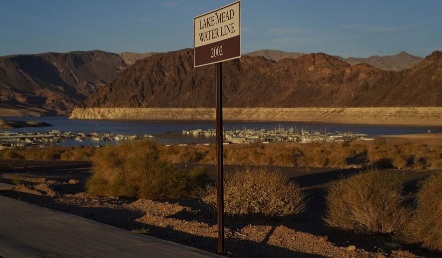 A sign marks the water line from 2002 near Lake Mead at the Lake Mead National Recreation Area, Saturday, July 9, 2022, near Boulder City, Nev. The largest U.S. reservoir has shrunken to a record low amid a punishing drought and the demands of 40 million people in seven states who are sucking the Colorado River dry. (AP Photo/John Locher)