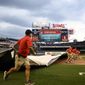 The scoreboard warns of inclement weather in the area as the Washington Nationals grounds crew rolls out the tarp on the field before a baseball game between the Nationals and the Seattle Mariners, Tuesday, July 12, 2022, in Washington. (AP Photo/Nick Wass)