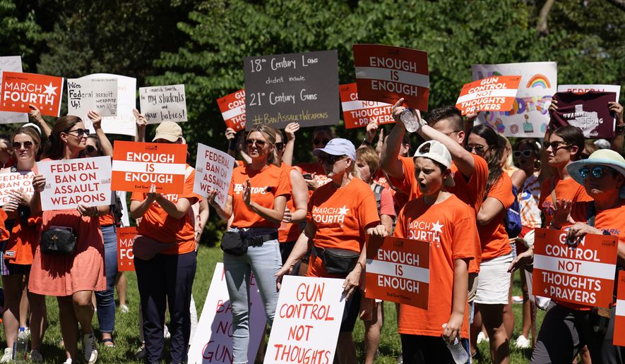 Demonstrators hold signs at a rally held by March Fourth near the U.S. Capitol on Wednesday, July 13, 2022, in Washington, that was calling for universal background checks for guns and an assault weapons ban in the wake of continued mass shootings. (AP Photo/Mariam Zuhaib)