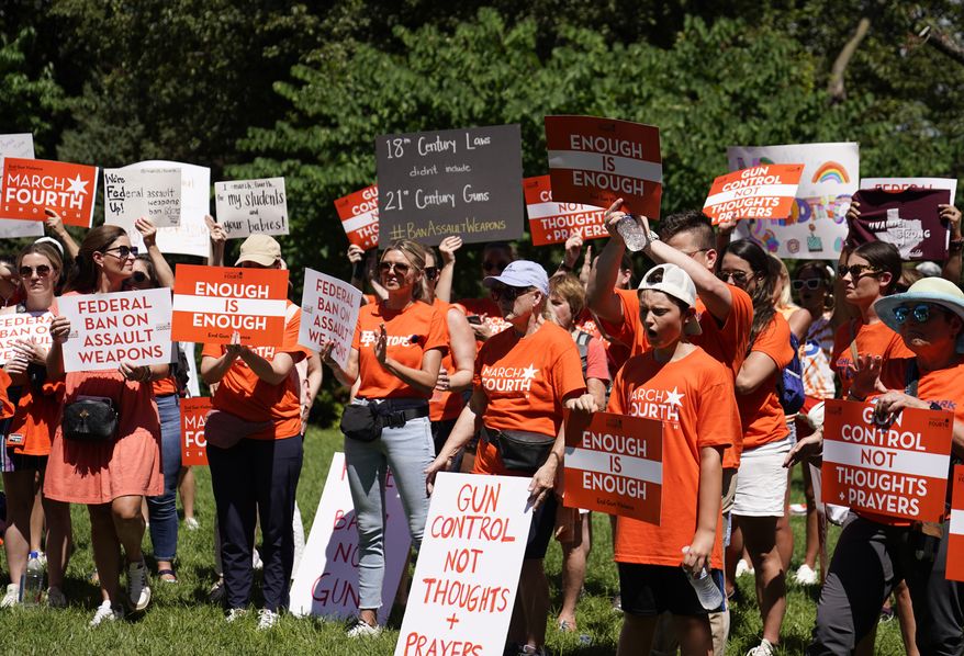 Demonstrators hold signs at a rally held by March Fourth near the U.S. Capitol on Wednesday, July 13, 2022, in Washington, that was calling for universal background checks for guns and an assault weapons ban in the wake of continued mass shootings. (AP Photo/Mariam Zuhaib)