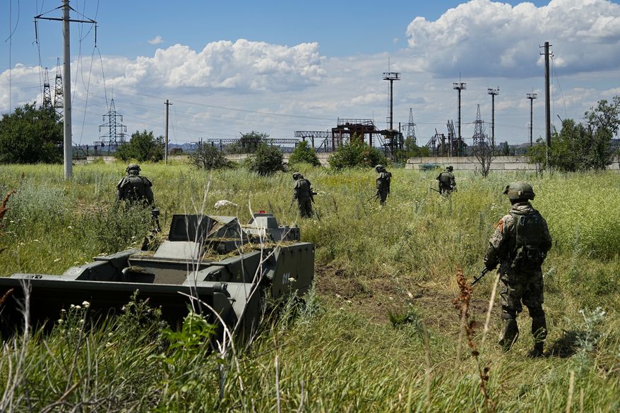 Russian mine clearing experts work to find and defuse mines along the high voltage line in Mariupol, on the territory which is under the Government of the Donetsk People&#x27;s Republic control, eastern Ukraine, Wednesday, July 13, 2022. This photo was taken during a trip organized by the Russian Ministry of Defense. (AP Photo)