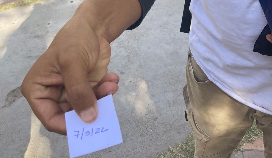 On May 21, 2022, a migrant displays an appointment slip to be interviewed at Casa del Migrante migrant services center on May 7, 2022 for possible entry to the United States. The interview was canceled after overwhelming demand. (AP Photo/Elliot Spagat)