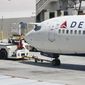 A tug driver pushes a Delta Air Lines Boeing 737 back from a gate, Thursday, July 7, 2022, at the Fort Lauderdale-Hollywood International Airport in Fort Lauderdale, Fla. Delta Air Lines said Wednesday, July 13, 2022, that it earned $735 million in the second quarter. Earnings per share fell short of Wall Street expectations, however, which the airline blamed on high fuel prices and more than 4,000 canceled flights in May and June. (AP Photo/Wilfredo Lee)