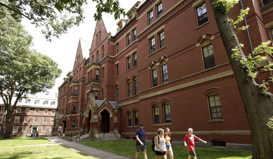 In this Tuesday, July 16, 2019 photo people walk along a sidewalk on the campus of Harvard University, in Cambridge, Mass. (AP Photo/Steven Senne)
