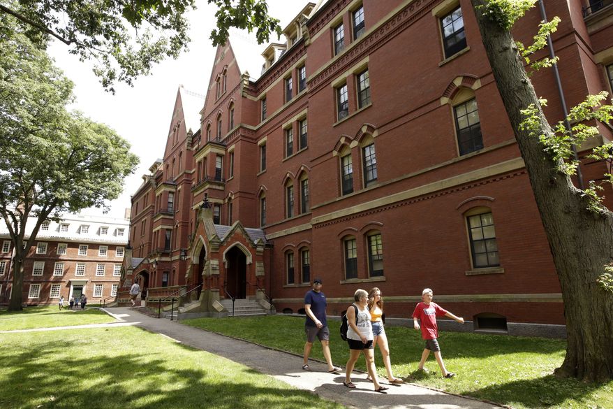 In this Tuesday, July 16, 2019 photo people walk along a sidewalk on the campus of Harvard University, in Cambridge, Mass. (AP Photo/Steven Senne) ** FILE **