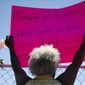 Cariol Horne, 54, holds up a sign as she stands outside the fenced-off parking lot outside Tops Friendly Market during a remembrance ceremony on Thursday, July 14, 2022, in Buffalo, N.Y. (AP Photo/Joshua Bessex)