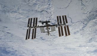 In this photo provided by NASA, backdropped against clouds over Earth, the International Space Station is seen from Space Shuttle Discovery as the two orbital spacecraft accomplish their relative separation on March 7, 2011. It was announced Friday, July 15, 2022, that NASA astronauts will go back to riding Russian rockets under a new agreement. At the same time, Russian cosmonauts will launch aboard U.S. rockets to the International Space Station beginning this fall. (NASA via AP, File)