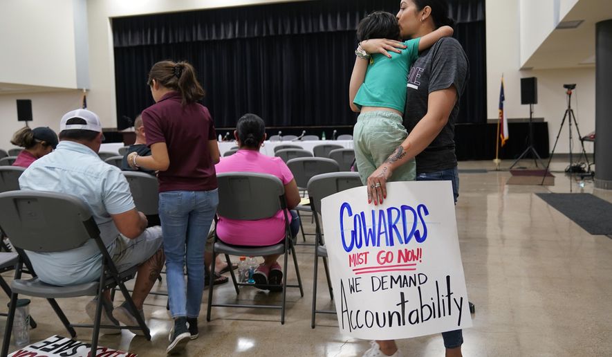 Rachel Martinez carries her son and a protest sign as she attends a city council meeting, on July 12, 2022, in Uvalde, Texas. A Texas lawmaker says surveillance video from the school hallway at Robb Elementary School where police waited as a gunman opened fire in a fourth-grade classroom will be shown this weekend to residents of Uvalde. (AP Photo/Eric Gay, File)