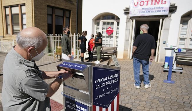 A voter submits a ballot in an official drop box during early voting in Athens, Ga., on Oct. 19, 2020. The widespread use of absentee ballot drop boxes during the 2020 election was largely trouble-free, contrary to claims made by former President Donald Trump and his Republican allies. An Associated Press survey of state election officials across the U.S. revealed no problems that could have affected the results, including from fraud, vandalism or theft. (AP Photo/John Bazemore, File)