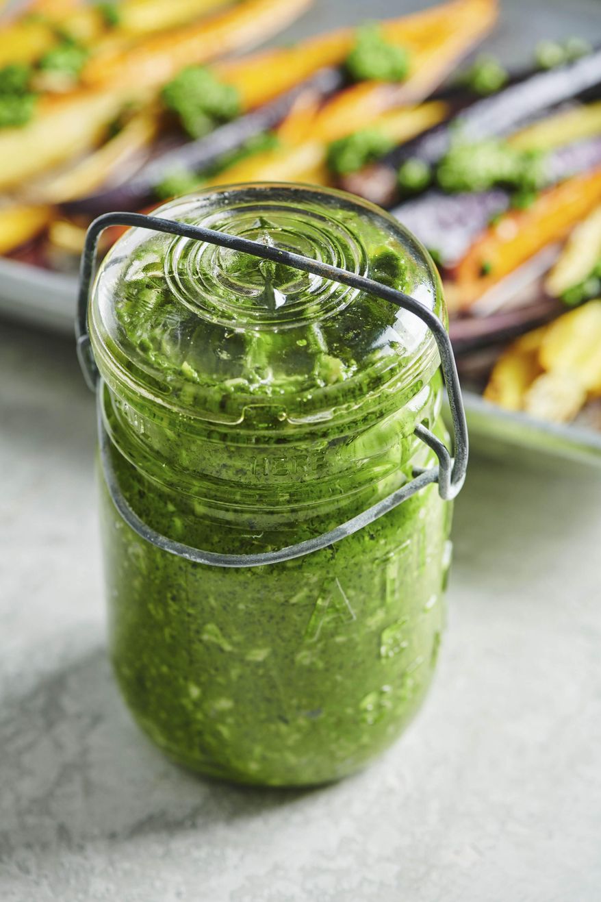 This March 2019 photo shows a jar of spinach and parsley pesto. Fresh herbs enhance all kinds of dishes in summertime and all year. If a garden is not in the cards for you, you can easily grow herbs in a windowsill pot. Many herbs thrive in containers, and then you can snip off little bunches of basil, dill, oregano and thyme to your heart’s content, knowing there will be more to come. (Cheyenne Cohen via AP)