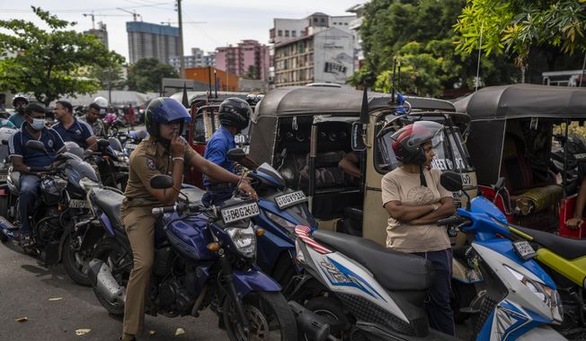 Sri Lankans wait in queue to buy petrol at a fuel station, in Colombo, Sri Lanka, July 17, 2022. (AP Photo/Rafiq Maqbool)