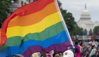 With the U.S. Capitol in the background, a person waves a rainbow flag as they participate in a rally in support of the LGBTQIA+ community at Freedom Plaza, Saturday, June 12, 2021, in Washington. (AP Photo/Jose Luis Magana, File)
