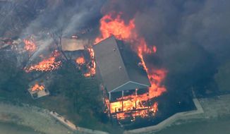 In this image taken from video, a structure burns during a wildfire in Palo Pinto County, Texas on Monday, July 18, 2022. A wildfire has burned at least five homes and resulted in about 300 homes being evacuated around a lake in north Texas amid sweltering temperatures and dry conditions, authorities said. (KDFW FOX 4 via AP)