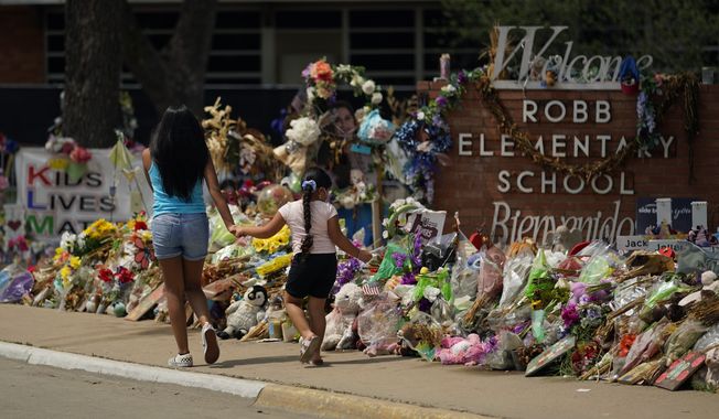 In this July 12, 2022, photo, Visitors walk past a makeshift memorial honoring those killed at Robb Elementary School, in Uvalde, Texas. Parents in Uvalde, Texas, are livid about the security lapses that contributed to the school shooting this spring. They&#x27;re terrified to send their kids back to school. Yet further securing schools -- such as through additional lockdown drills -- is controversial. (AP Photo/Eric Gay, FILE)