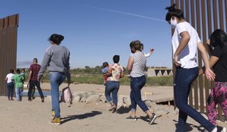 FILE - A group of Brazilian migrants make their way around a gap in the U.S.-Mexico border in Yuma, Ariz., seeking asylum in the U.S. after crossing over from Mexico, June 8, 2021. Two Republican border-state governors who are investing billions of dollars on immigration enforcement and hours at the podium blasting the Biden administration policies have found two unlikely allies: Democratic mayors Muriel Bowser of Washington, D.C., and Eric Adams of New York. The mayors&#39; recent overtures for federal aid is a response to Texas and Arizona busing migrants away from the border, a months-old practice that has been long on political theater and short on practical impact. (AP Photo/Eugene Garcia, File)