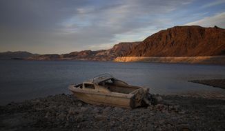 A formerly sunken boat sits high and dry along the shoreline of Lake Mead at the Lake Mead National Recreation Area, Tuesday, May 10, 2022, near Boulder City, Nev. Las Vegas area water officials want to cap the size of new swimming pools, citing worries about supplies from the drying-up Lake Mead reservoir on the drought-stricken Colorado River. (AP Photo/John Locher, File)