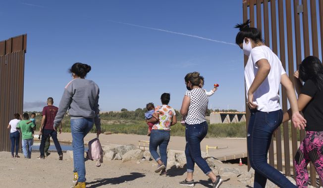 A group of Brazilian migrants make their way around a gap in the U.S.-Mexico border in Yuma, Ariz., seeking asylum in the U.S. after crossing over from Mexico, June 8, 2021. Two Republican border-state governors who are investing billions of dollars on immigration enforcement and hours at the podium blasting the Biden administration policies have found two unlikely allies: Democratic mayors Muriel Bowser of Washington, D.C., and Eric Adams of New York. The mayors&#x27; recent overtures for federal aid is a response to Texas and Arizona busing migrants away from the border, a months-old practice that has been long on political theater and short on practical impact. (AP Photo/Eugene Garcia, File)