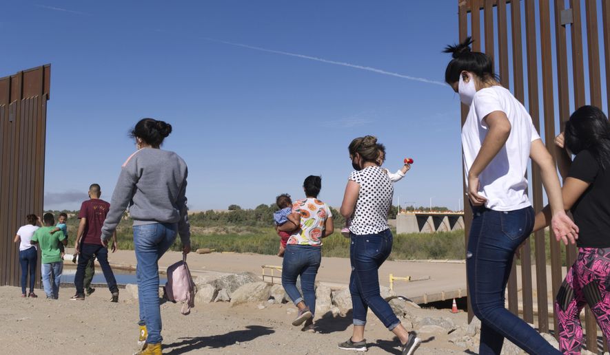A group of Brazilian migrants make their way around a gap in the U.S.-Mexico border in Yuma, Ariz., seeking asylum in the U.S. after crossing over from Mexico, June 8, 2021. Two Republican border-state governors who are investing billions of dollars on immigration enforcement and hours at the podium blasting the Biden administration policies have found two unlikely allies: Democratic mayors Muriel Bowser of Washington, D.C., and Eric Adams of New York. The mayors&#39; recent overtures for federal aid is a response to Texas and Arizona busing migrants away from the border, a months-old practice that has been long on political theater and short on practical impact. (AP Photo/Eugene Garcia, File)