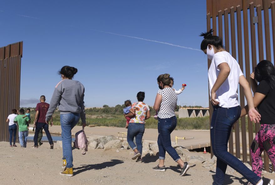 A group of Brazilian migrants make their way around a gap in the U.S.-Mexico border in Yuma, Ariz., seeking asylum in the U.S. after crossing over from Mexico, June 8, 2021. Two Republican border-state governors who are investing billions of dollars on immigration enforcement and hours at the podium blasting the Biden administration policies have found two unlikely allies: Democratic mayors Muriel Bowser of Washington, D.C., and Eric Adams of New York. The mayors&#x27; recent overtures for federal aid is a response to Texas and Arizona busing migrants away from the border, a months-old practice that has been long on political theater and short on practical impact. (AP Photo/Eugene Garcia, File)
