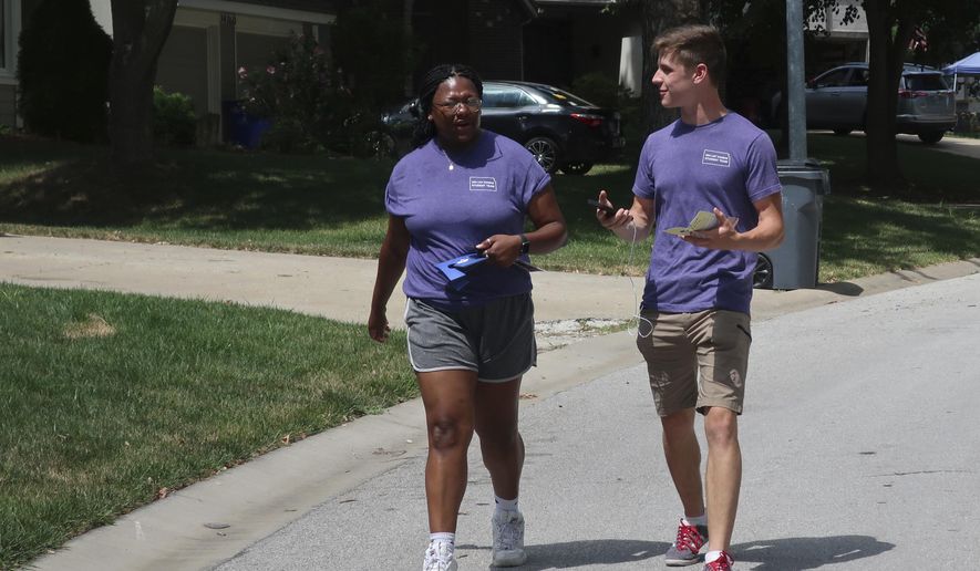 College students Alyssa Winters, left, and Ben Kennedy, right, chat as they go door-to-door to talk to prospective voters about a proposed amendment to the Kansas Constitution that would allow legislators to further restrict or ban abortion, Friday, July 8, 2022, in Olathe, Kansas. They are among about 300 college students brought into Kansas by the Susan B. Anthony Pro-Life America group, which backs the measure. (AP Photo/John Hanna)