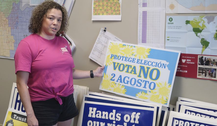 Jessica Porter, communications chair for the Shawnee County, Kansas, Democratic Party, discusses a sign in Spanish urging voters to oppose a proposed amendment to the Kansas Constitution to allow legislators to further restrict or ban abortion, Friday, July 15, 2022, in Topeka, Kansas. The proposed amendment is a response to a 2019 Kansas Supreme Court decision protecting abortion rights. (AP Photo/John Hanna)
