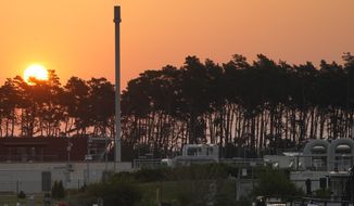 The sun rises behind the landfall facility of the Nord Stream 1 Baltic Sea pipeline and the transfer station of the OPAL gas pipeline, the Baltic Sea Pipeline Link, in Lubmin, Germany, Thursday, July 21, 2022. (AP Photo/Markus Schreiber)