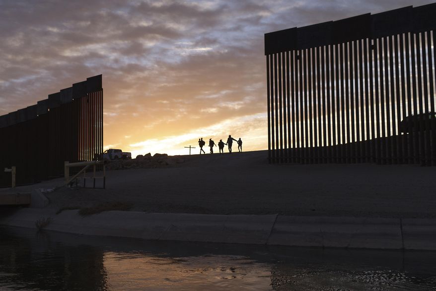 A pair of migrant families from Brazil pass through a gap in the border wall to reach the United States after crossing from Mexico to Yuma, Ariz., to seek asylum on June 10, 2021. (AP Photo/Eugene Garcia) **FILE**