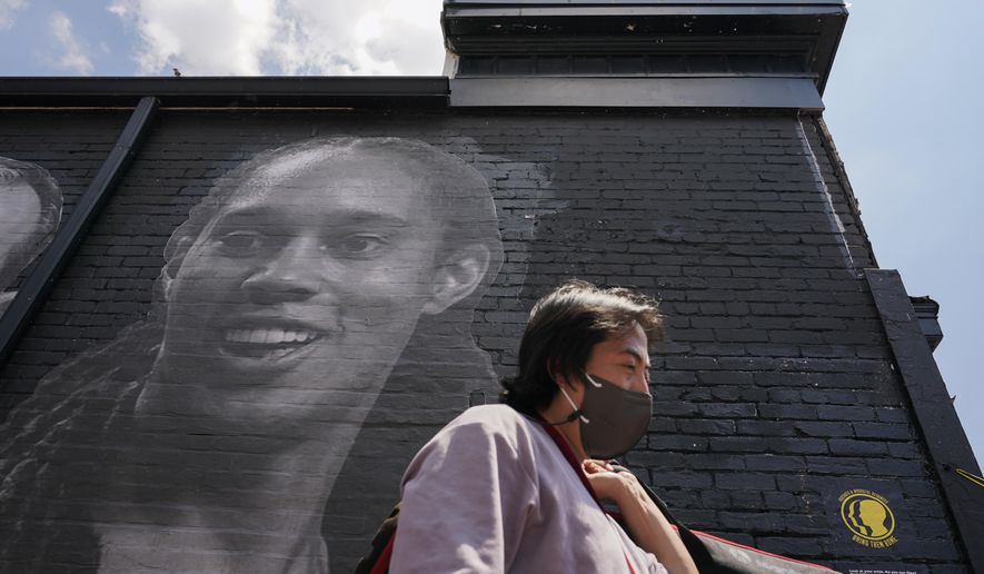 A visitor walks down an alley past a mural depicting WNBA star Brittney Griner, top left, and other American hostages and wrongful detainees who are being held abroad, Wednesday, July 20, 2022, in the Georgetown neighborhood of Washington. (AP Photo/Patrick Semansky)
