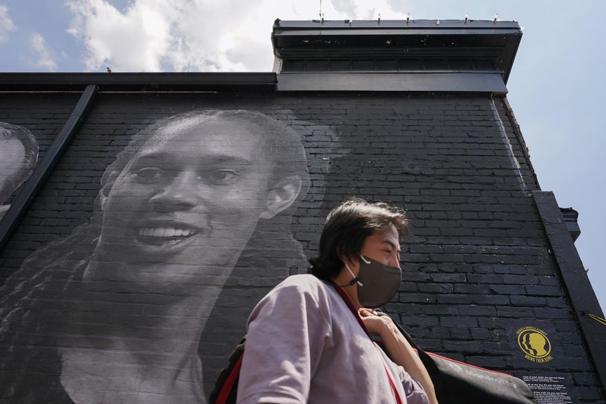 A visitor walks down an alley past a mural depicting WNBA star Brittney Griner, top left, and other American hostages and wrongful detainees who are being held abroad, Wednesday, July 20, 2022, in the Georgetown neighborhood of Washington. (AP Photo/Patrick Semansky)