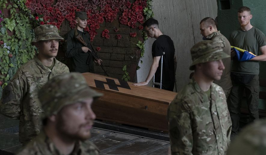 Soldiers of the Azov regiment pay their last respects to a serviceman killed in battle against Russian troops, in a city crematorium in Kyiv, Ukraine, Thursday, July 21, 2022. (AP Photo/Andrew Kravchenko)