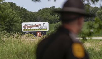 An Iowa State Patrolman walks past a Maquoketa Caves State Park sign as police investigate a shooting that left several people dead, Friday, July 22, 2022, in Maquoketa, Iowa. The campground was evacuated in the wake of the shooting. (Nikos Frazier/Quad City Times via AP)