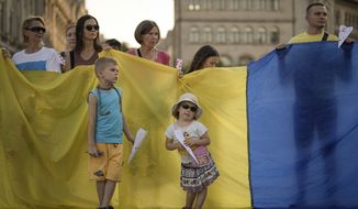 People hold paper planes and the Ukrainian flag during a protest by Ukrainian refugees in Bucharest, Romania, Saturday, July 23, 2022. Dozens of Ukrainian refugees shouted anti-Russia slogans and distributed paper planes inscribed with the hashtag #terroRussia calling on world leaders to designate Russia as a terrorism sponsor state. (AP Photo/Vadim Ghirda)