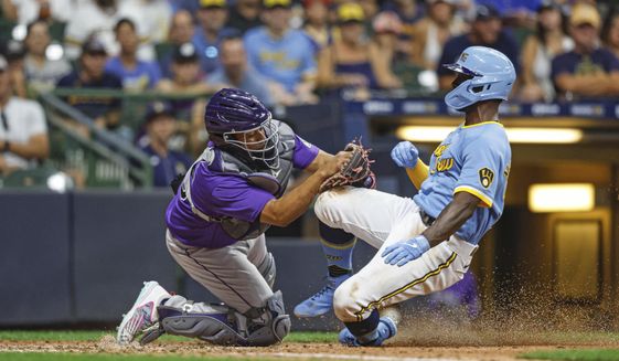 Colorado Rockies catcher Elias Diaz (35) tags out Milwaukee Brewers&#39; Andrew McCutchen (24) during the sixth inning of a baseball game Friday, July 22, 2022, in Milwaukee. (AP Photo/Jeffrey Phelps)